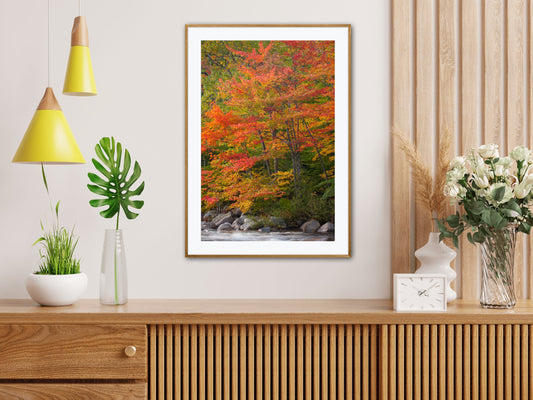 Framed autumn landscape print on a wall above a wooden console table with decorative items.